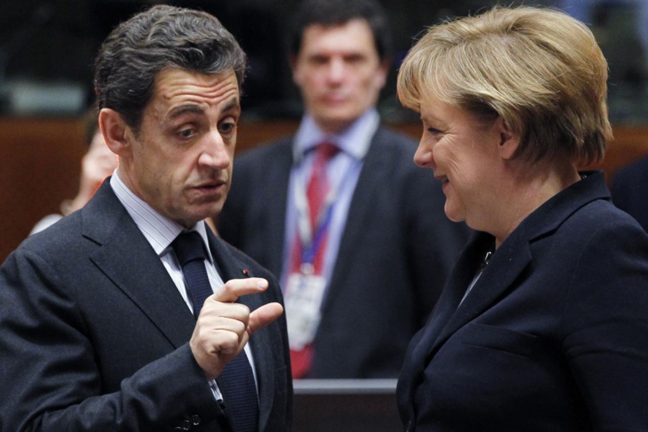 'French President Nicolas Sarkozy talks to German Chancellor Angela Merkel (R) during an European Union leaders summit in Brussels December 17, 2010. EU leaders have agreed to try to lengthen the matu