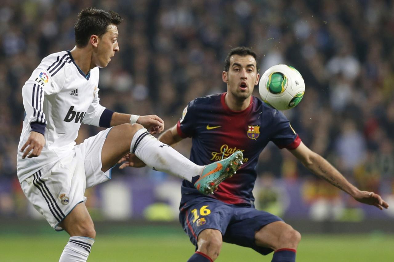 'Real Madrid\'s Mesut Ozil (L) fights for the ball with Barcelona\'s Sergio Busquets during their Spanish King\'s Cup semi final first leg soccer match at Santiago Bernabeu stadium in Madrid, January 