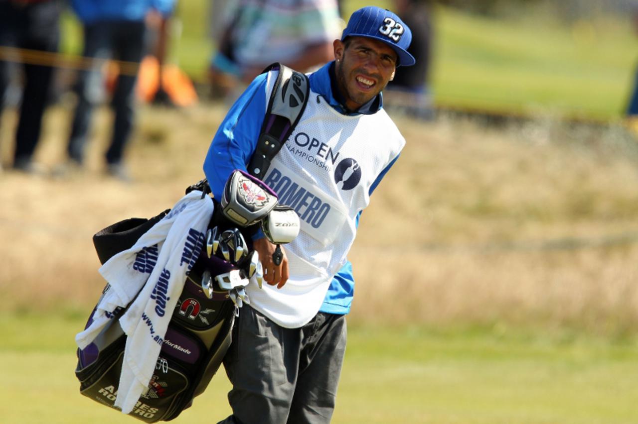 'Manchester City\'s Argentinian footballer Carlos Tevez carries the bag of Andres Romero of Argentina on the 13th fairway during his final round on day four of the 2012 British Open Golf Championship 