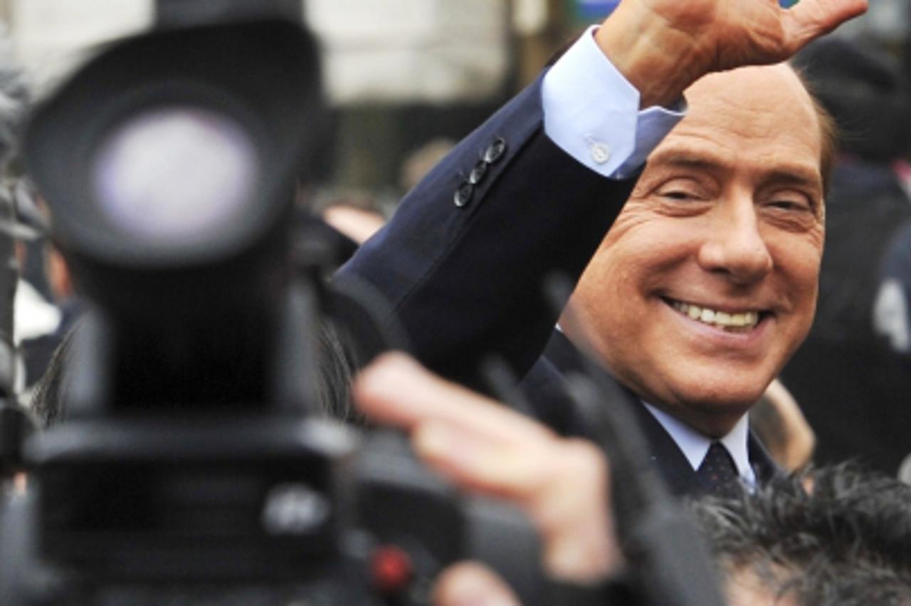 \'Italy\'s Prime Minister Silvio Berlusconi gestures as he leaves the Justice Palace in Milan March 28, 2011. Berlusconi appeared in court for the first time in almost eight years on Monday, in a tria