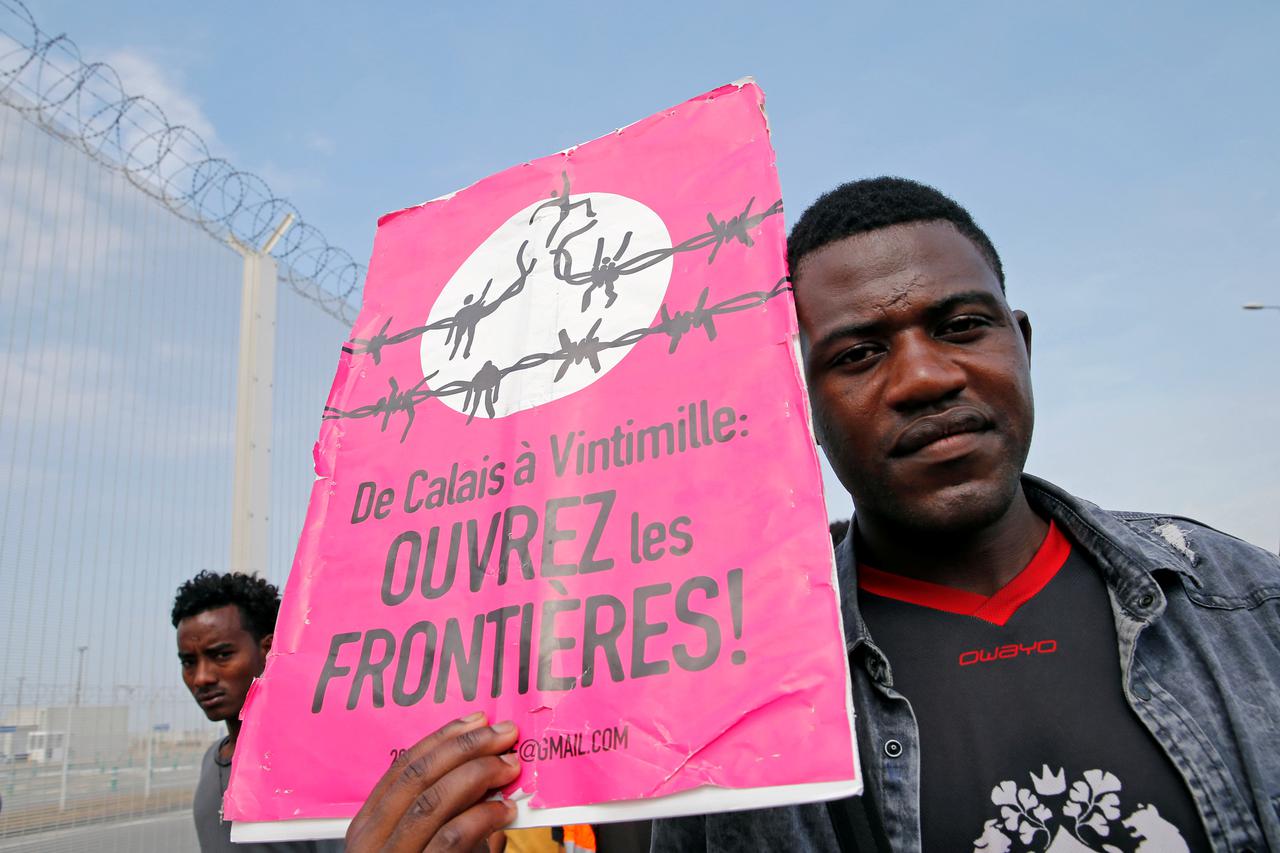 Migrant drži natpis "Otvorite granice" u Calaisu