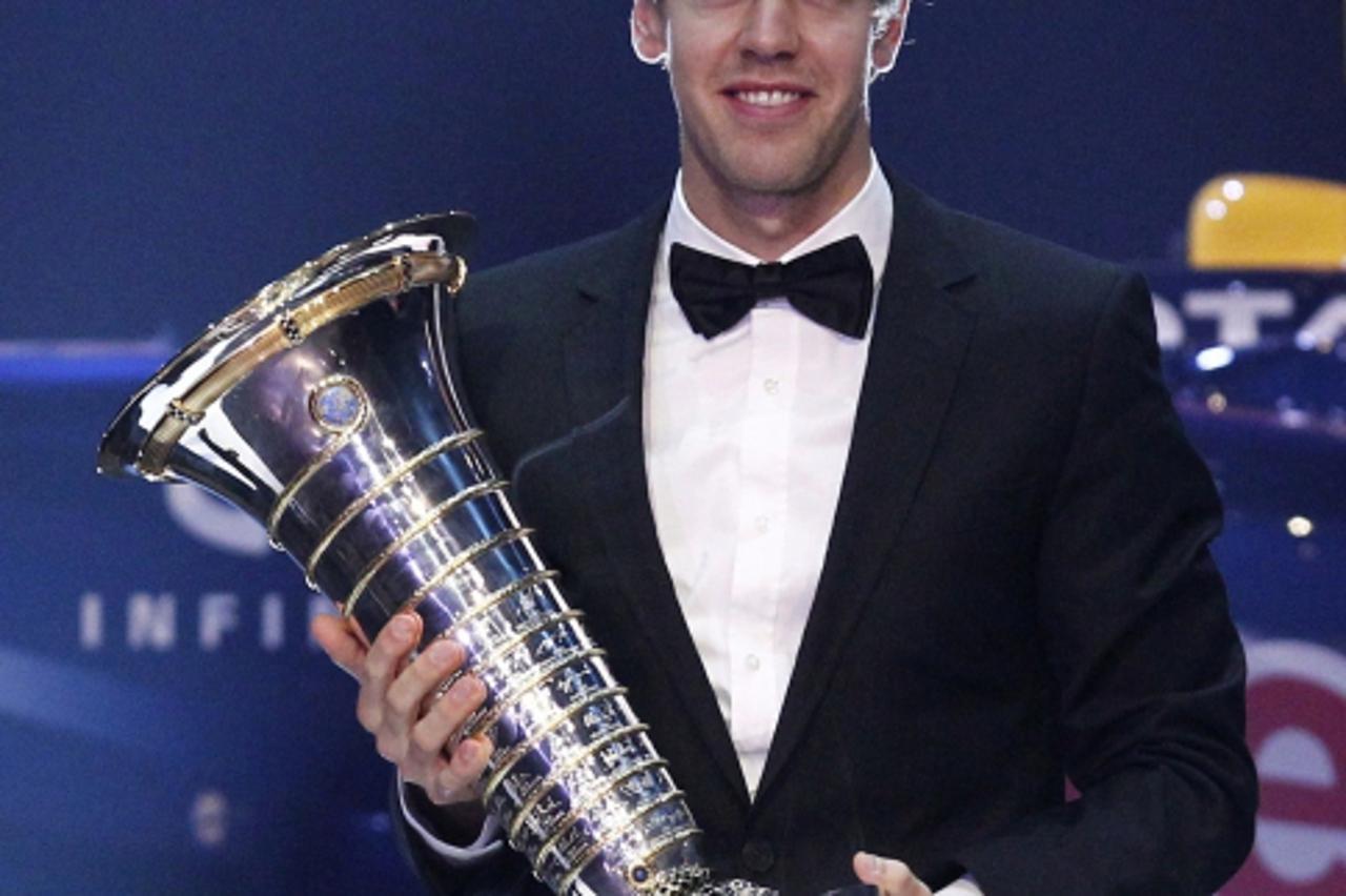 'Red Bull Formula One driver Sebastian Vettel of Germany poses with his FIA trophy during the 2011 Federation Internationale de l\'Automobile (FIA) gala night in Gurgaon, some 35 kms west of New Delhi