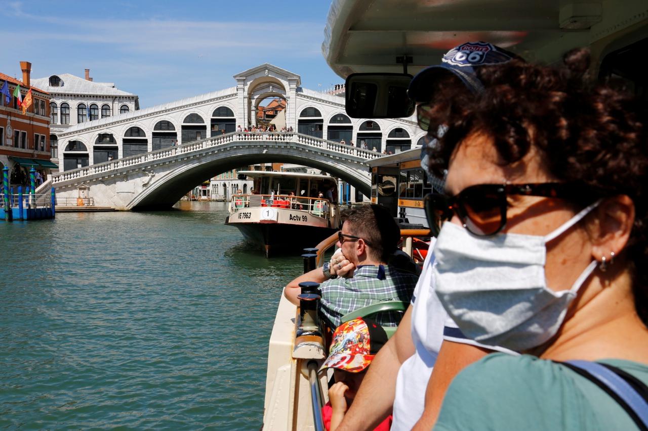 Tourists wear face masks as they pass the Rialto Bridge on a vaporetto (water taxi), amid the coronavirus disease (COVID-19) outbreak, in Venice