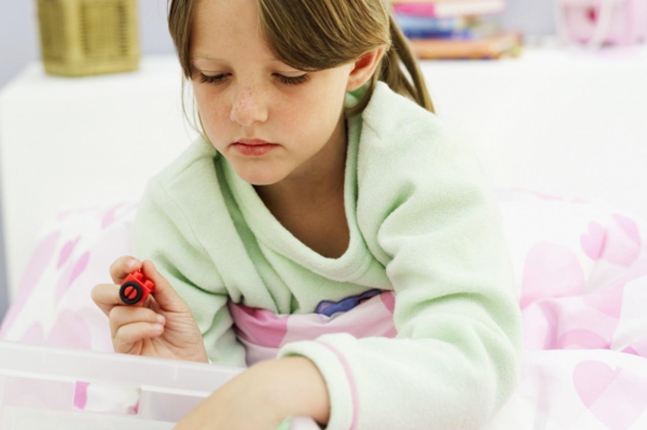 'Close-up of a young girl (5-6) looking through a box of toys'