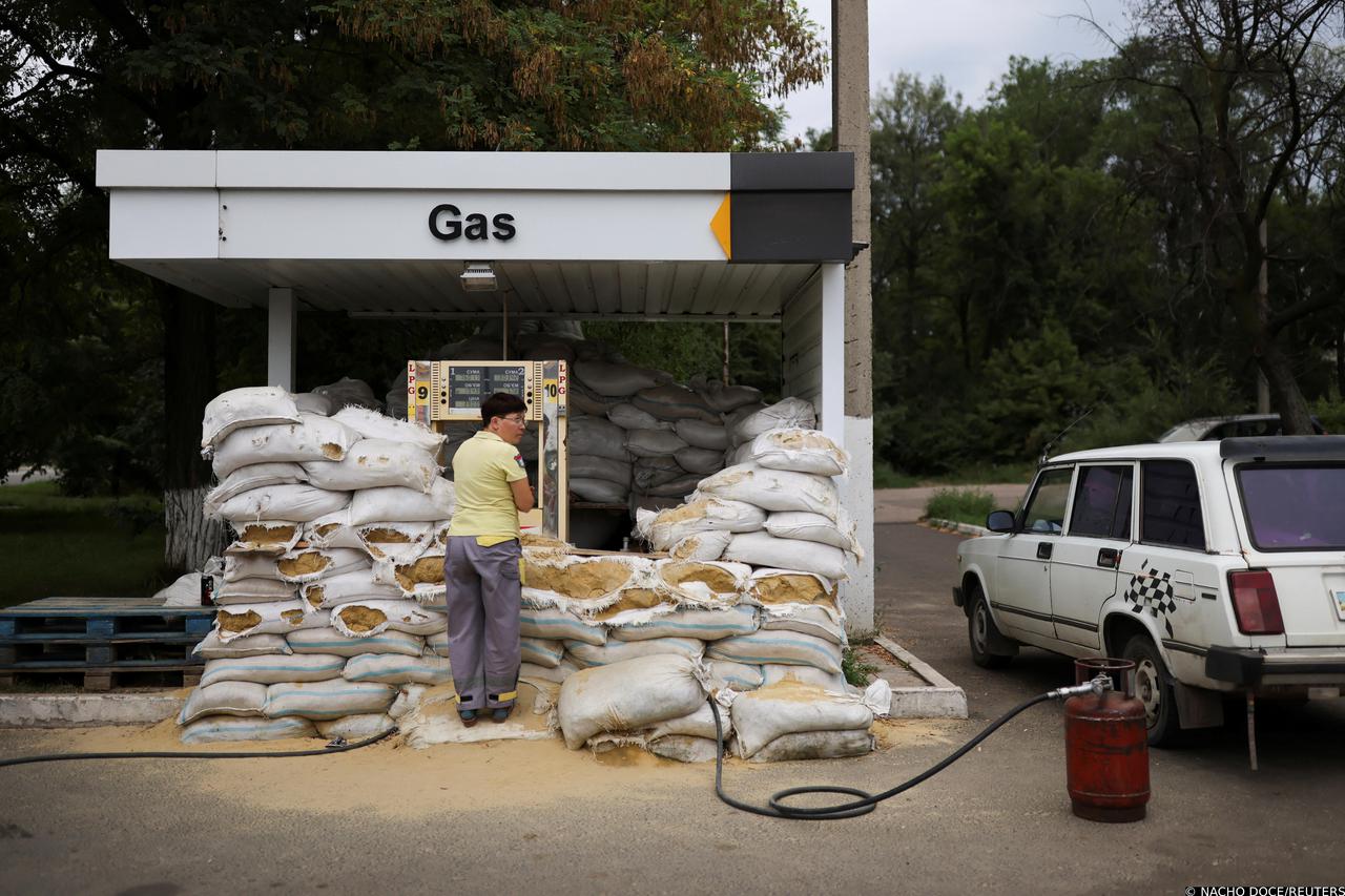 Sandbags for protection are placed as a worker refills a gas cylinder at a petrol station in Konstantynivka