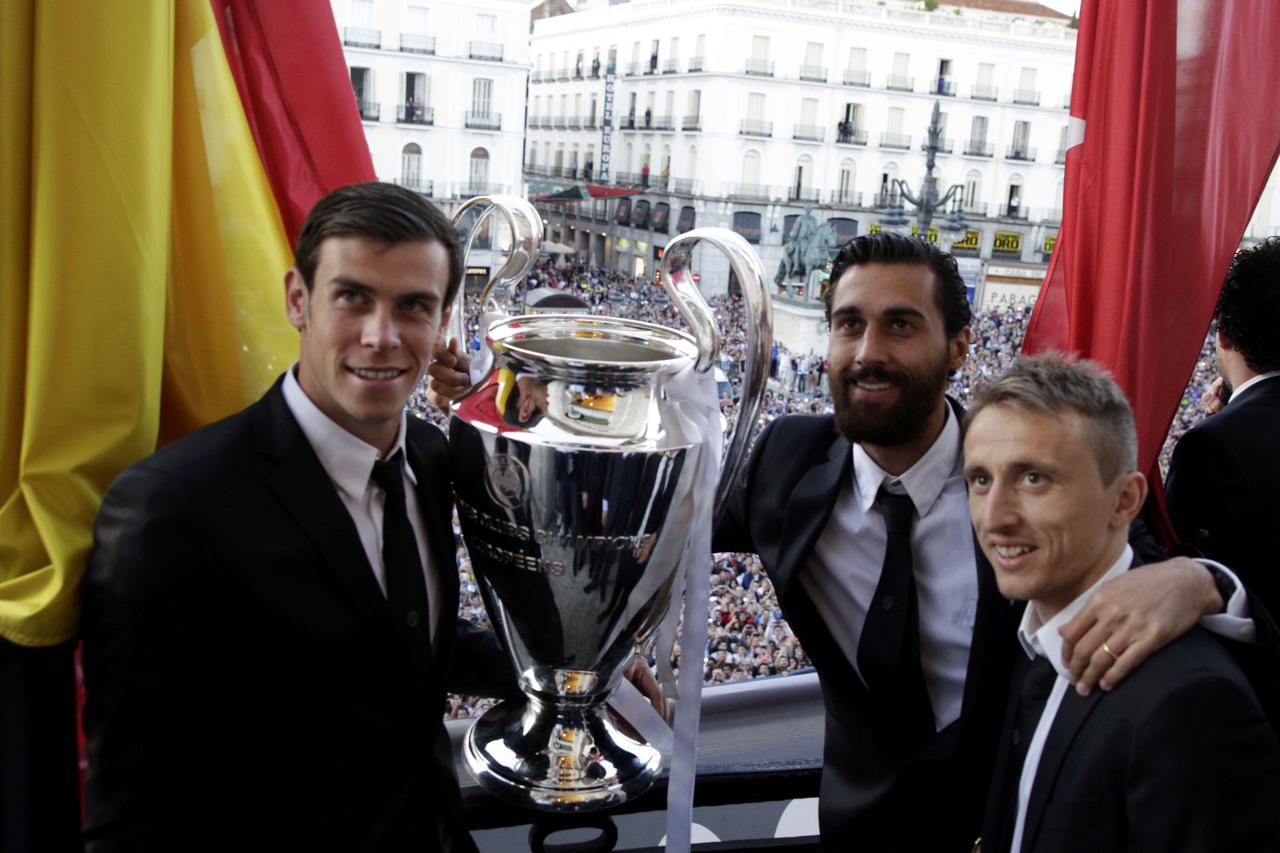 Real Madrid's Gareth Bale (L), Alvaro Arbeloa (C) and Luka Modric pose with the Champions League trophy in a balcony at Madrid's Community headquarters in Madrid May 25, 2014. Real Madrid won its 10th Champions League title after beating Atletico Madrid i