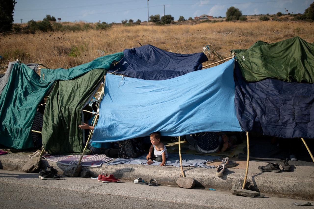 A baby sits in a tent as refugees and migrants from the destroyed Moria camp are sheltered near a new temporary camp, on the island of Lesbos