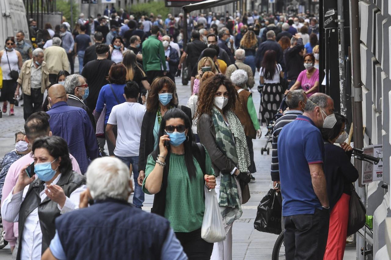 A crowd of people wearing protective masks walk in Naples center