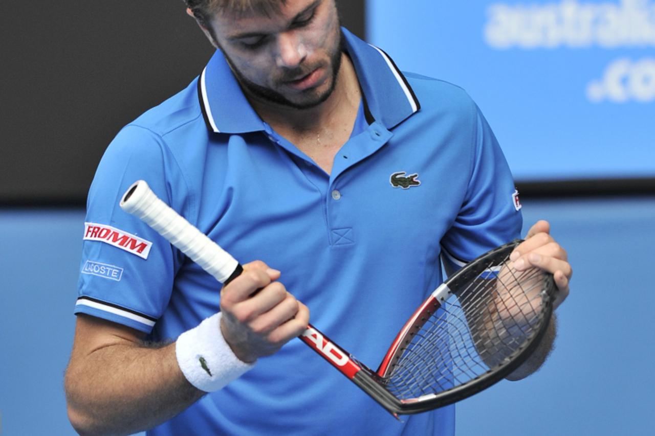 'Stanislas Wawrinka of Switzerland folds up his broken racquet after smashing it on the ground in reaction to losing a point during his quarter-final men\'s singles match against Roger Federer of Swit