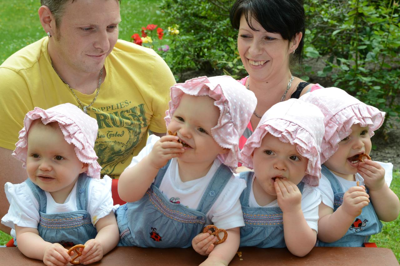 The identical quadruplets Laura, Jasmin, Kim and Sophie (L-R) sit with their parents Janett and Marcus Mehnert in their garden in Leipzig, Germany, 24 June 2013. Next month the one and a half year olds will start nursery school next month. Mother Janett M