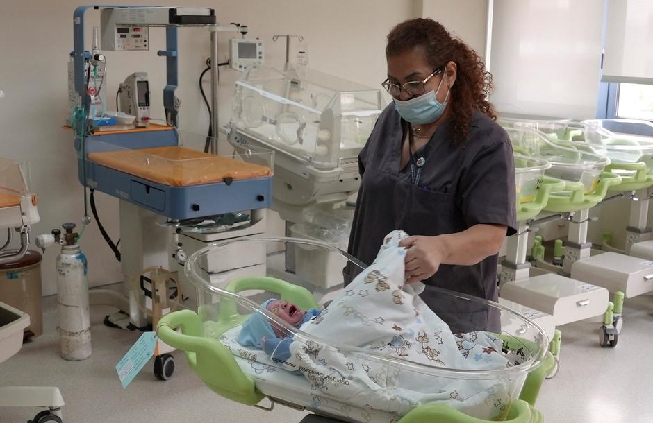 A medical worker checks on a newborn baby at a maternity ward inside a hospital as the world's population surged past 8 billion