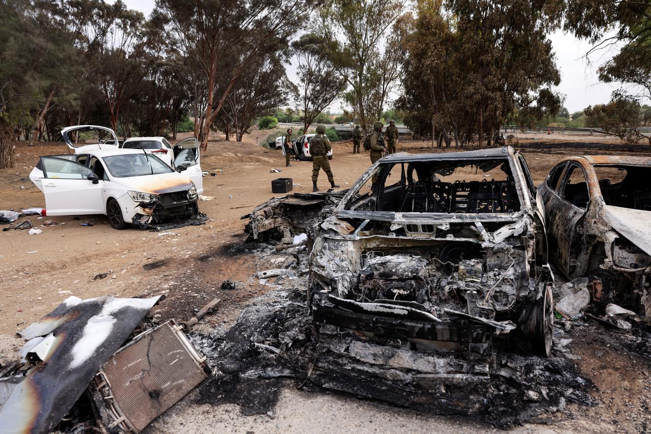 Israeli soldiers inspect burnt cars that are abandoned in a carpark near where a festival was held before an attack by Hamas gunmen from Gaza that left at least 260 people dead, by Israel's border with Gaza in southern Israel
