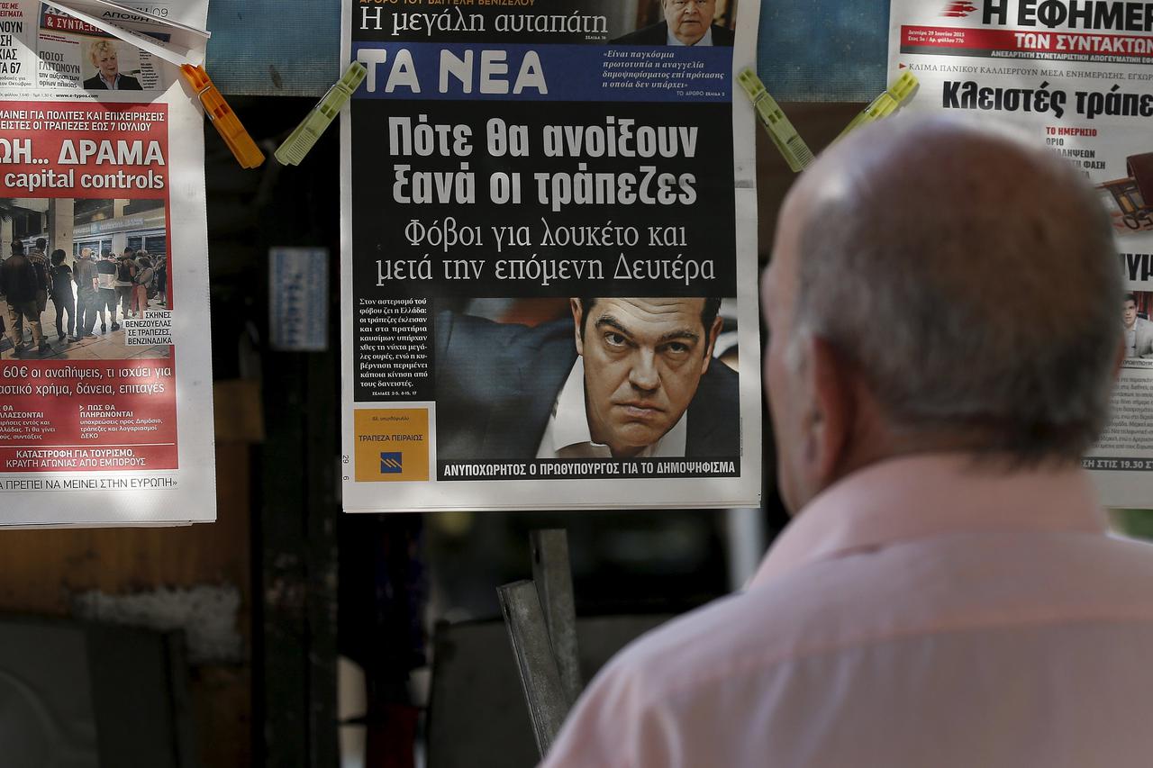 A man reads the front pages of various newspaper hanging at a kiosk in Athens, Greece June 29, 2015. Greece closed its banks and imposed capital controls on Sunday to check the growing strains on its crippled financial system, bringing the prospect of bei