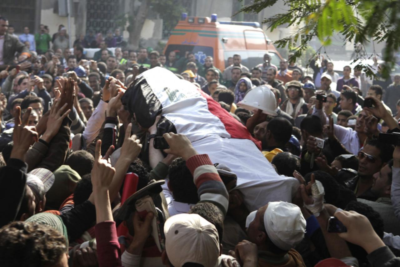 \'Protesters attend a funeral as health workers transfer the body of a protester killed during clashes between security forces and protesters near Tahrir Square in Cairo December 19, 2011. Egyptian se