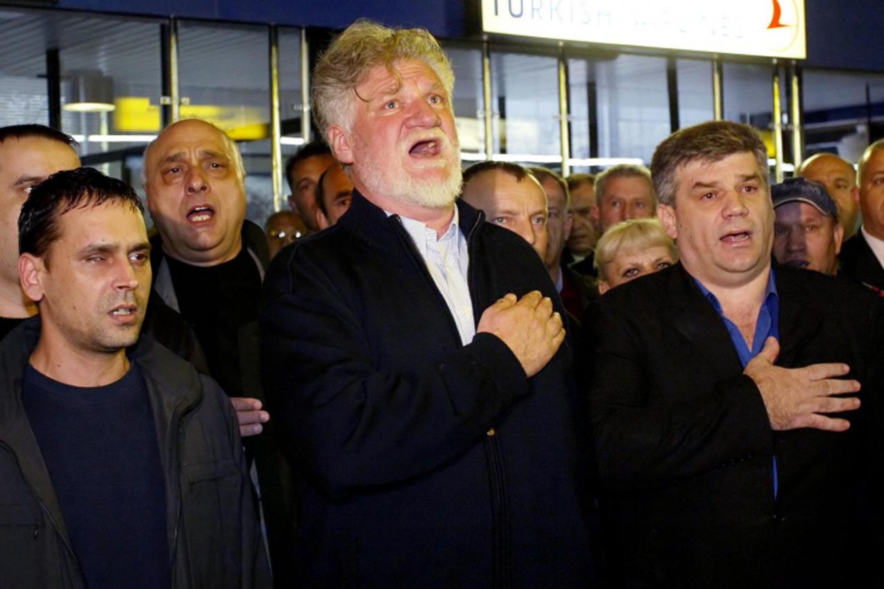 'Retired Croatian General Slobodan Praljak (C) sings the national anthem at Zagreb airport 05 April 2004 before leaving for the UN war crimes tribunal in the Hague. Six former Bosnian Croat officials 