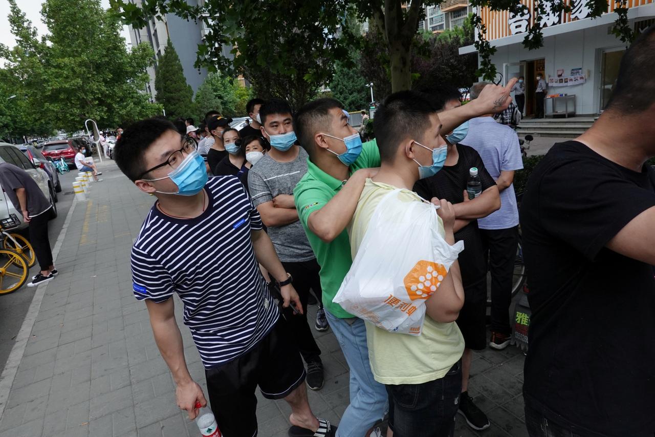 People wearing face masks wait in a line to receive nucleic acid tests in Beijing