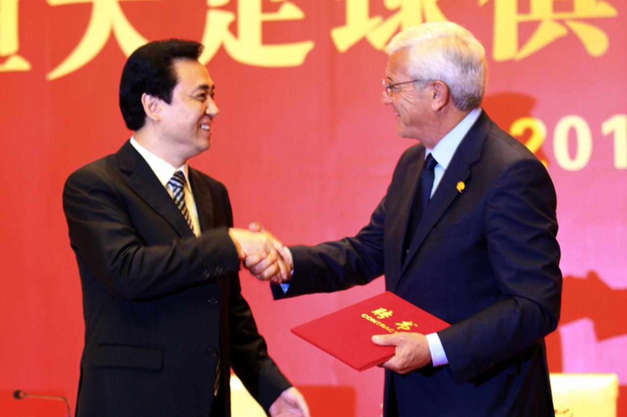 \'Italian coach Marcello Lippi (R) shakes hands with Guangzhou Evergrande\'s chairman Xu Jiayin (L) during a signing ceremony in Guangzhou, southern China\'s Guangdong province on May 17, 2012.  China