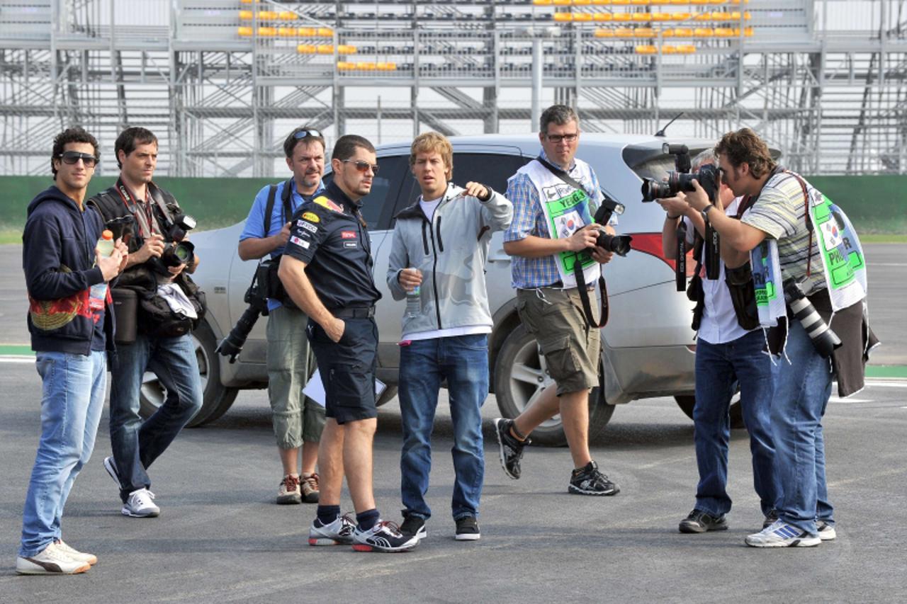 \'Red Bull Renault driver Sebastian Vettel (C) of Germany is surrounded by photographers as he walks along the track of the Korean International Circuit ahead Formula One\'s Korean Grand Prix in Yeong