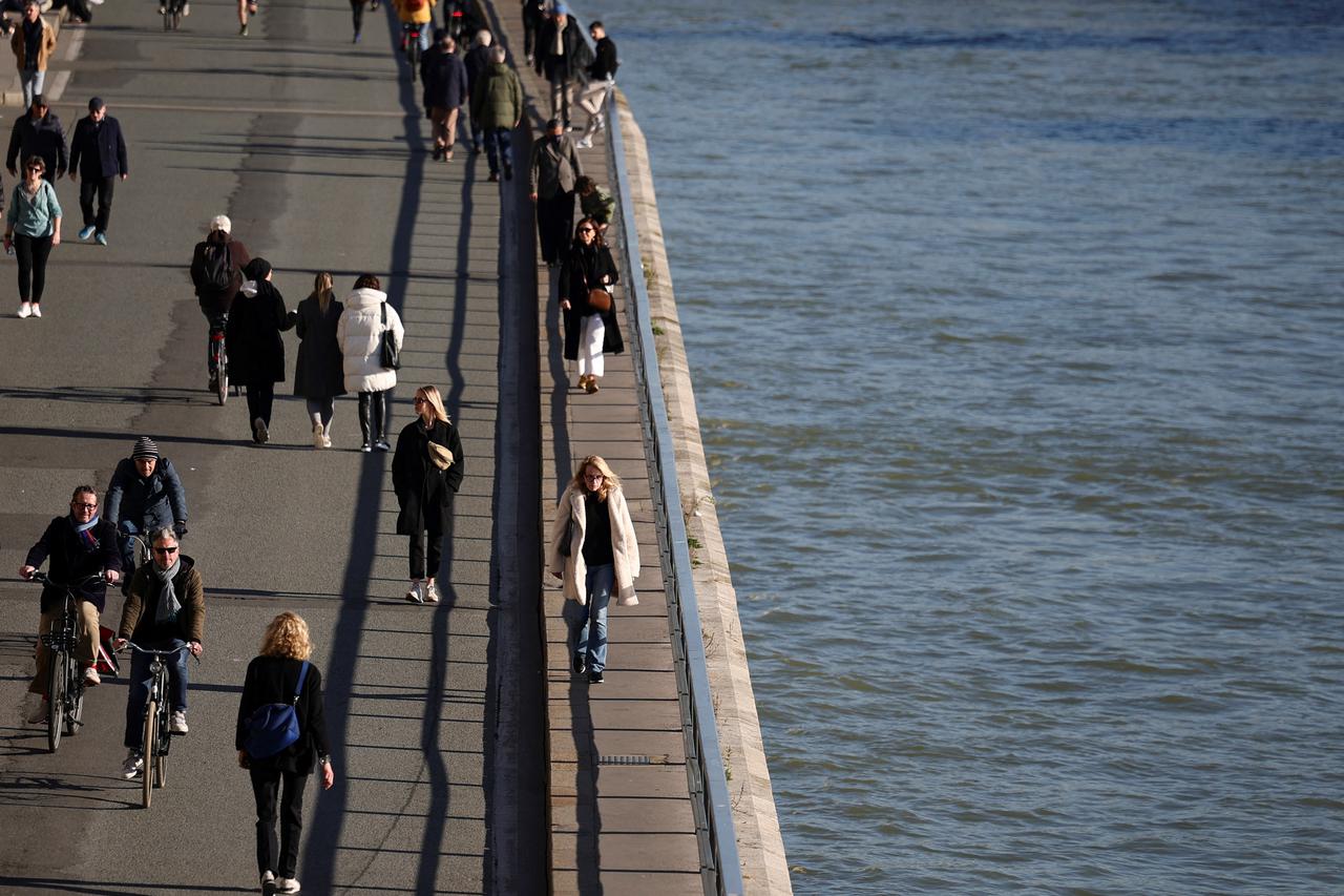 People walk on the banks of the river Seine, in Paris