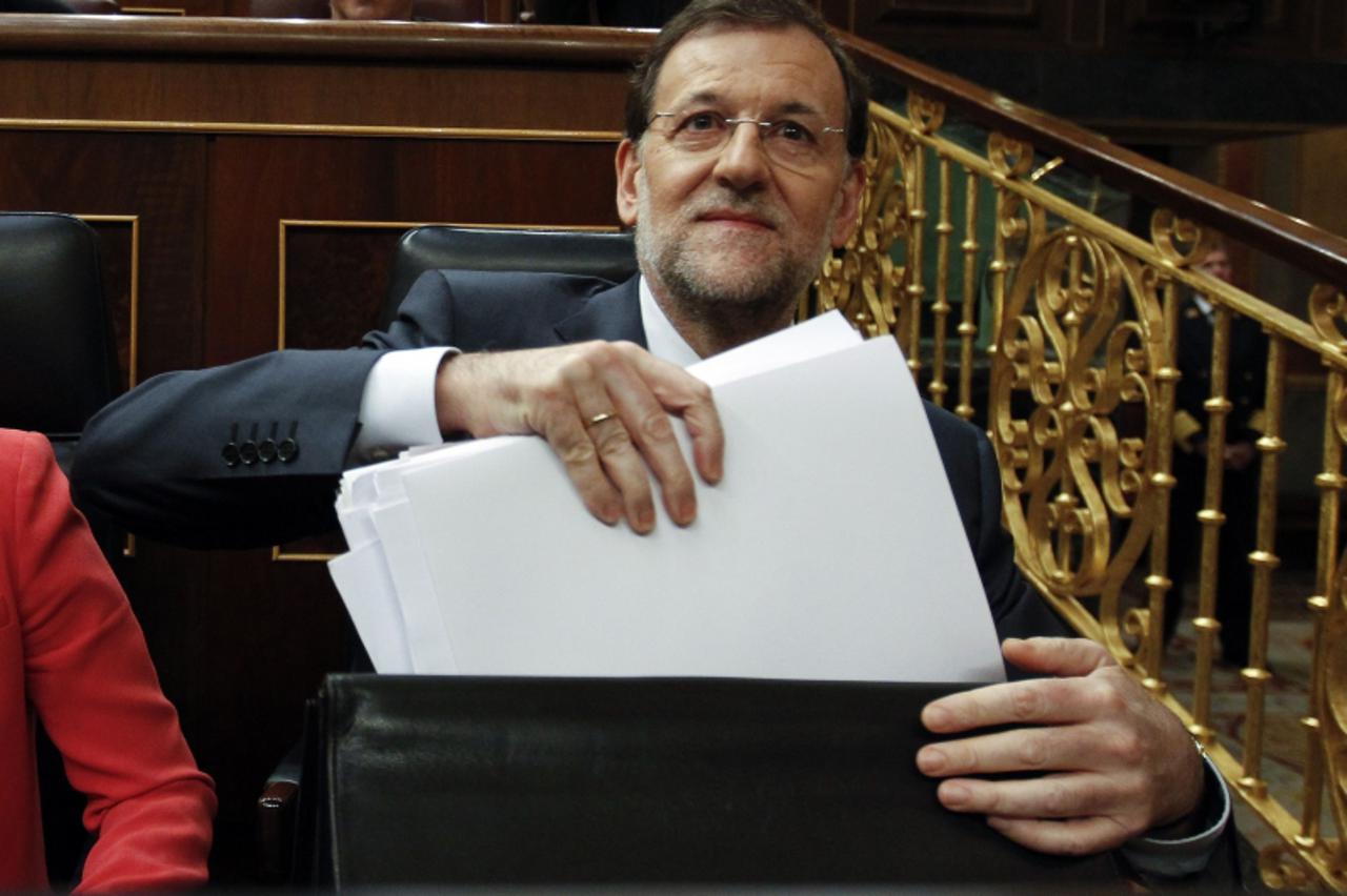 'Spain's Prime Minister Mariano Rajoy takes documents from his briefcase in parliament in Madrid, July 11, 2012.  Rajoy said on Wednesday he would raise the value-added tax by 3 percentage points to 