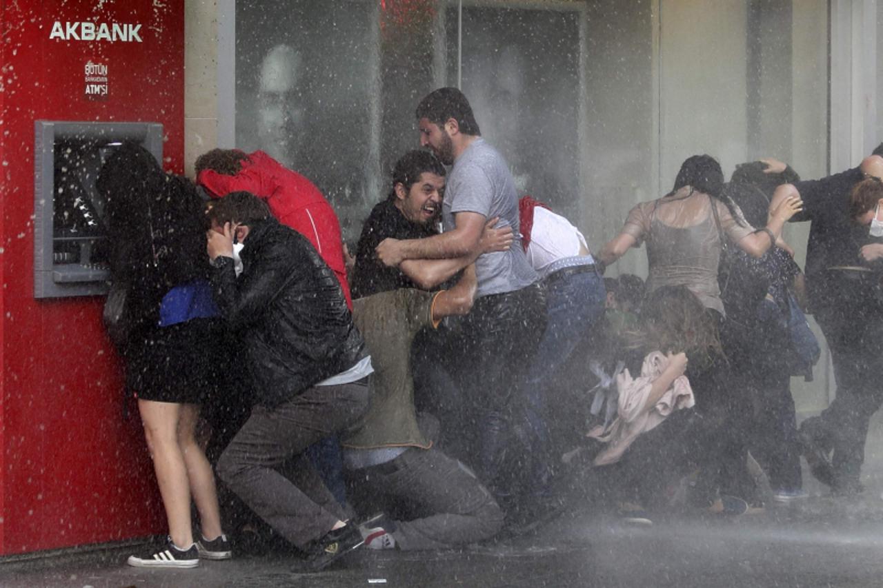 'REFILE - CORRECTING SPELLING OF CANNON Anti-government protesters try to protect themselves from a water cannon as riot police disperse them during a protest in Ankara June 5, 2013. Turkish demonstra