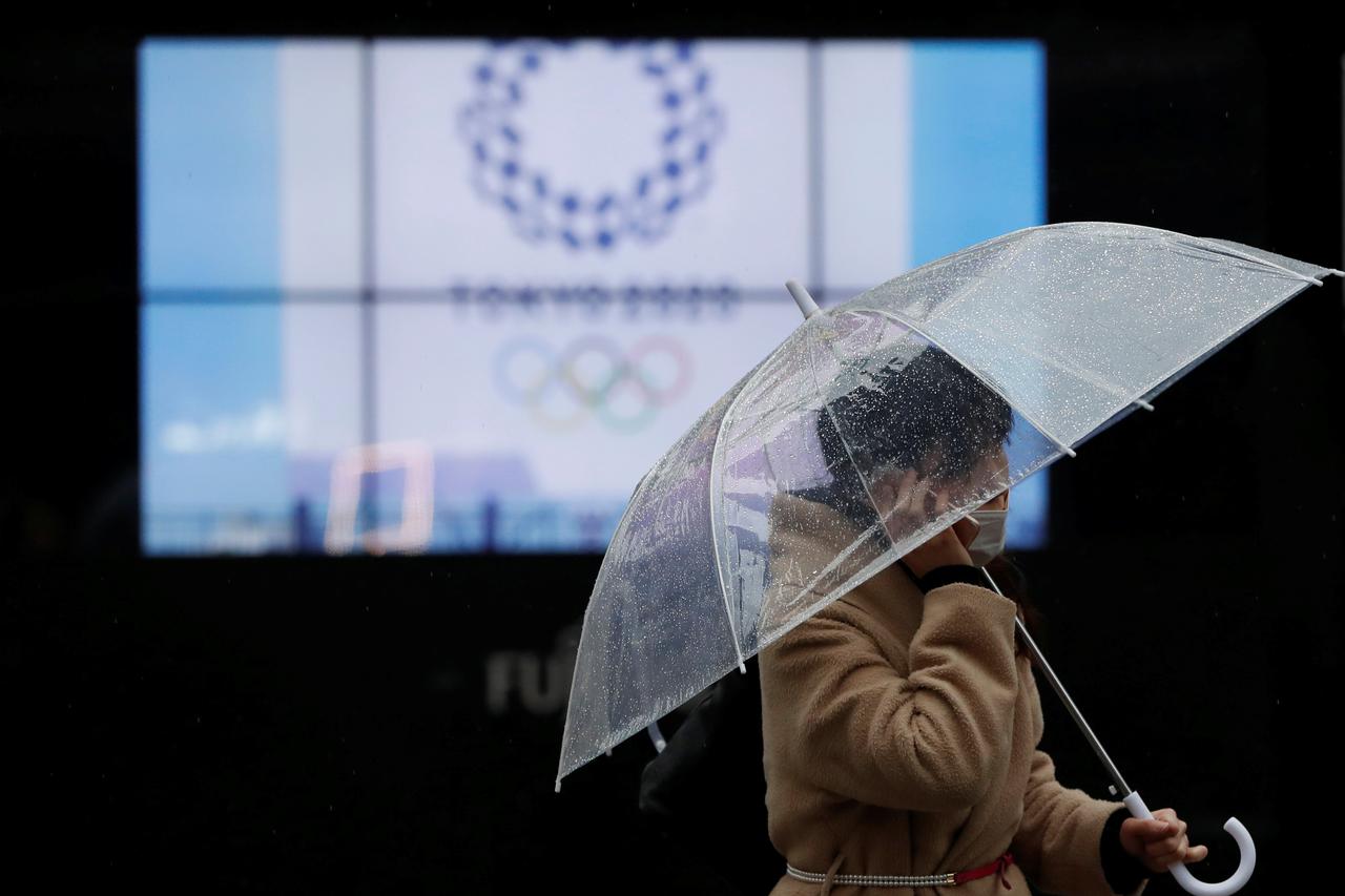 A passerby wearing a protective face mask walks past a display showing the logo of Tokyo 2020 Olympic Games, amid the coronavirus disease (COVID-19) outbreak in Tokyo