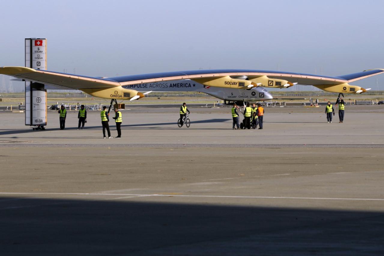 'Crew members walk the Solar Impulse to its hangar following a test flight at Moffett Field in Mountain View, California April 19, 2013. The aircraft, made of carbon fiber sheets and powered by solar 