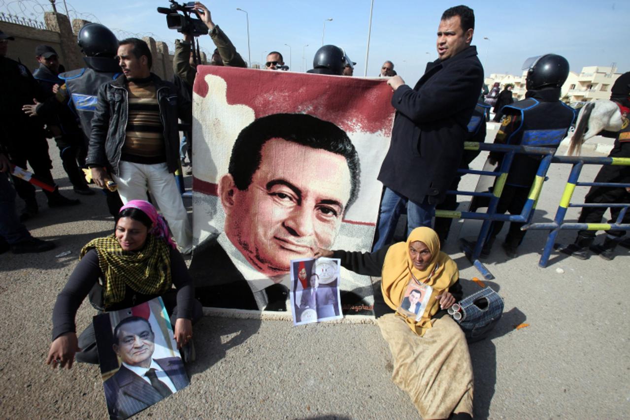 'epa03063578 Pro-Mubarak protesters shout slogans and hold pictures depicting the former Egyptian President Hosni Mubarak during his trial, outside Police Academy in Cairo, Egypt, 17 January 2012. For
