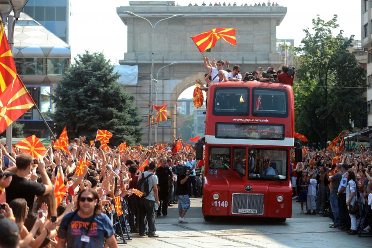 'Members of the Macedonian national basketball team are cheered by fans while riding on the slashed roof double-decker bus on their triumphant return to Skopje, on September 19, 2011. The Macedonian b