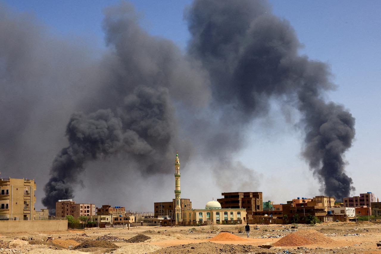 FILE PHOTO: Man walks while smoke rises above buildings after aerial bombardment in Khartoum North