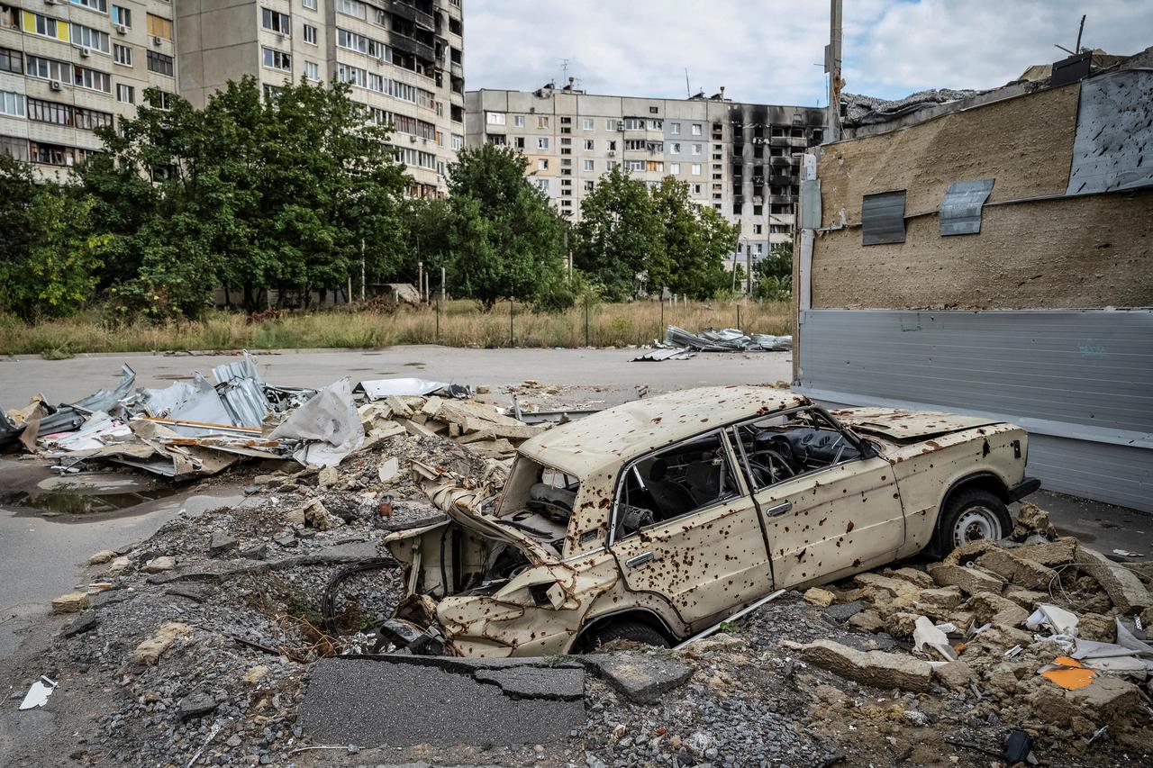A destroyed car is pictured in front of a damaged residential building, in Saltivka, one of the most damaged residential areas in Kharkiv