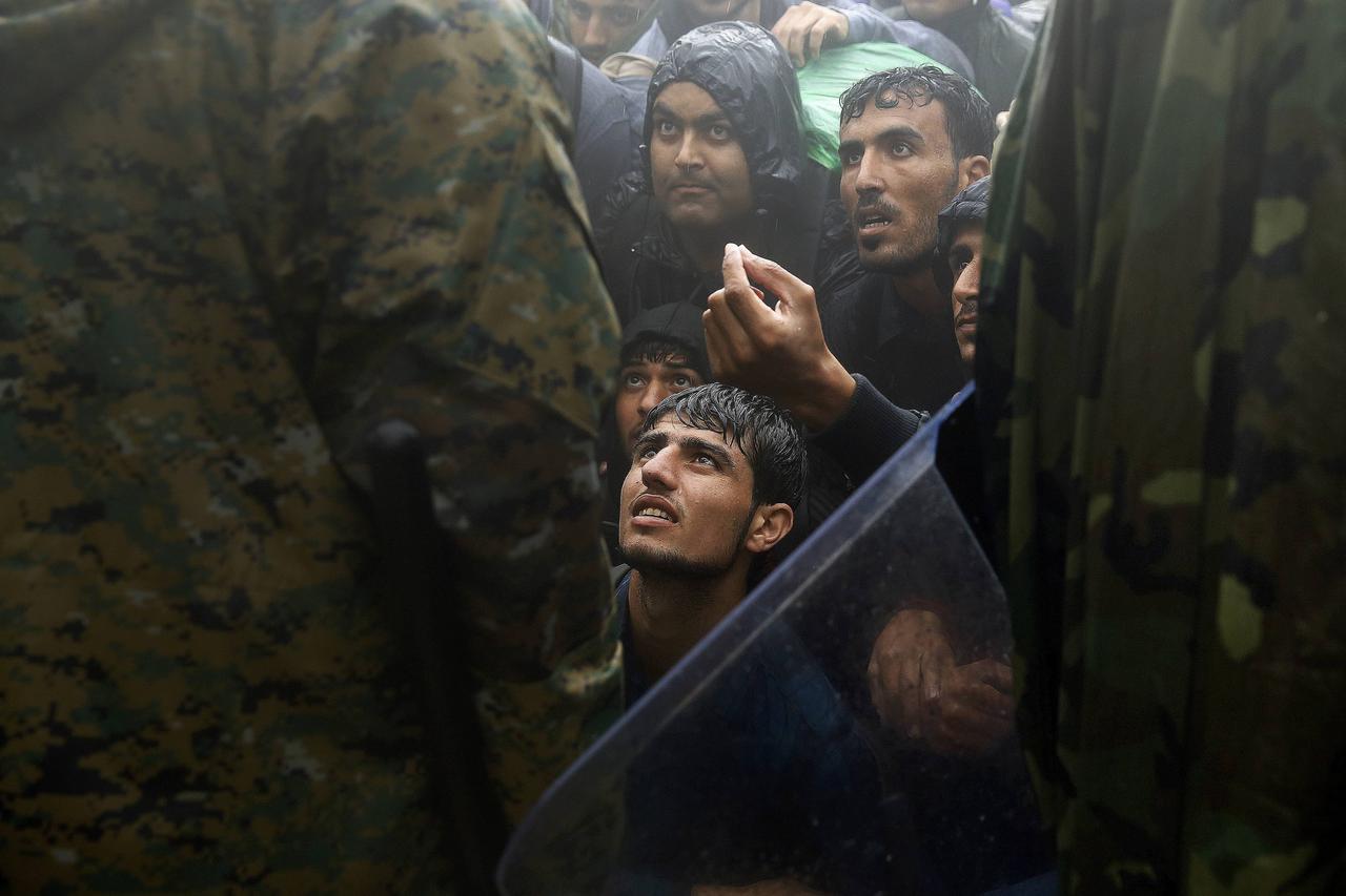 Migrants and refugees beg Macedonian soldiers to allow passage to cross the border from Greece into Macedonia during a rainstorm, near the Greek village of Idomeni, September 10, 2015. Most of the people flooding into Europe are refes fleeing violence and