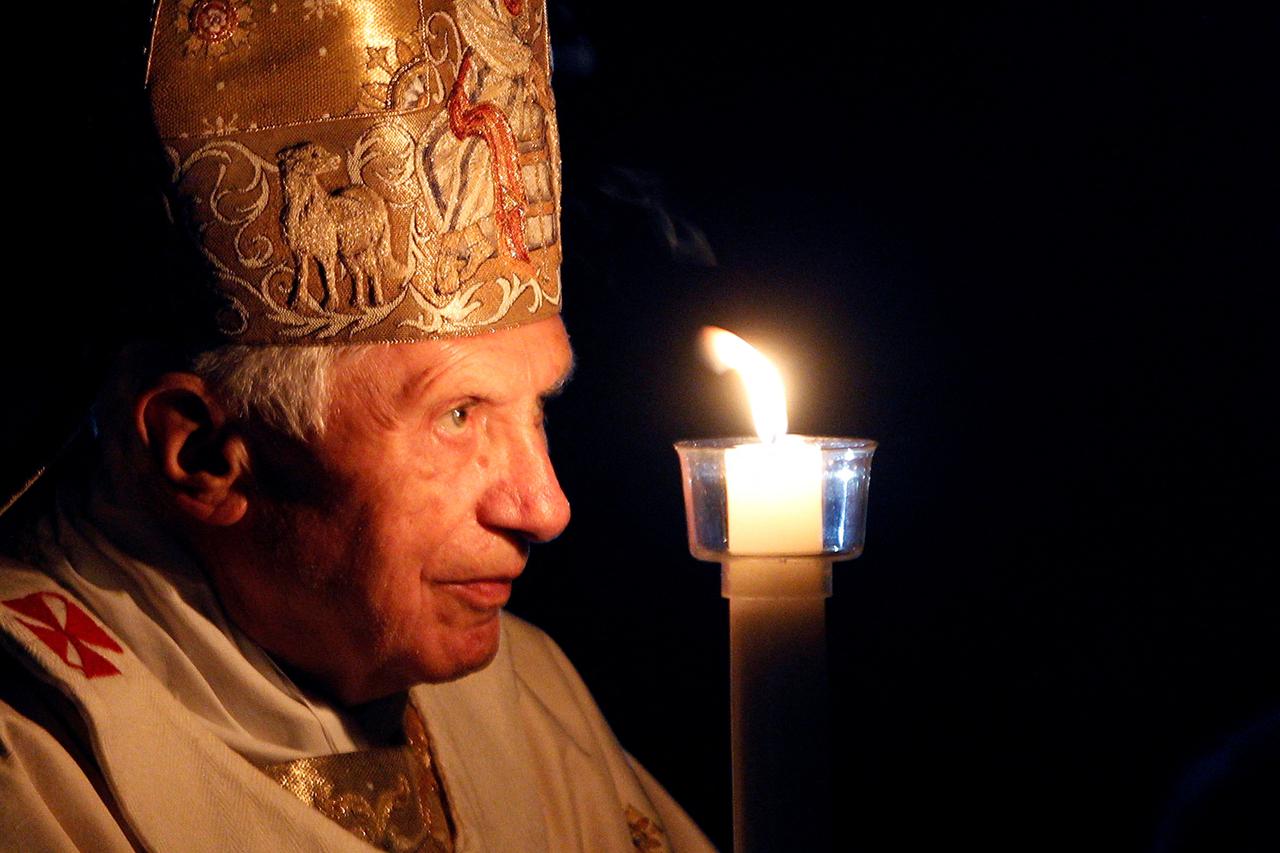 FILE PHOTO: Pope Benedict XVI prays while holding a candle light as he arrives to lead a vigil mass during Easter celebrations in the Vatican