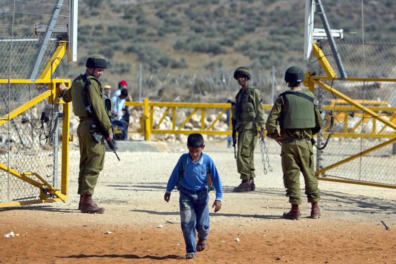 Palestinski dječak prolazi pokraj izraelskih vojnika