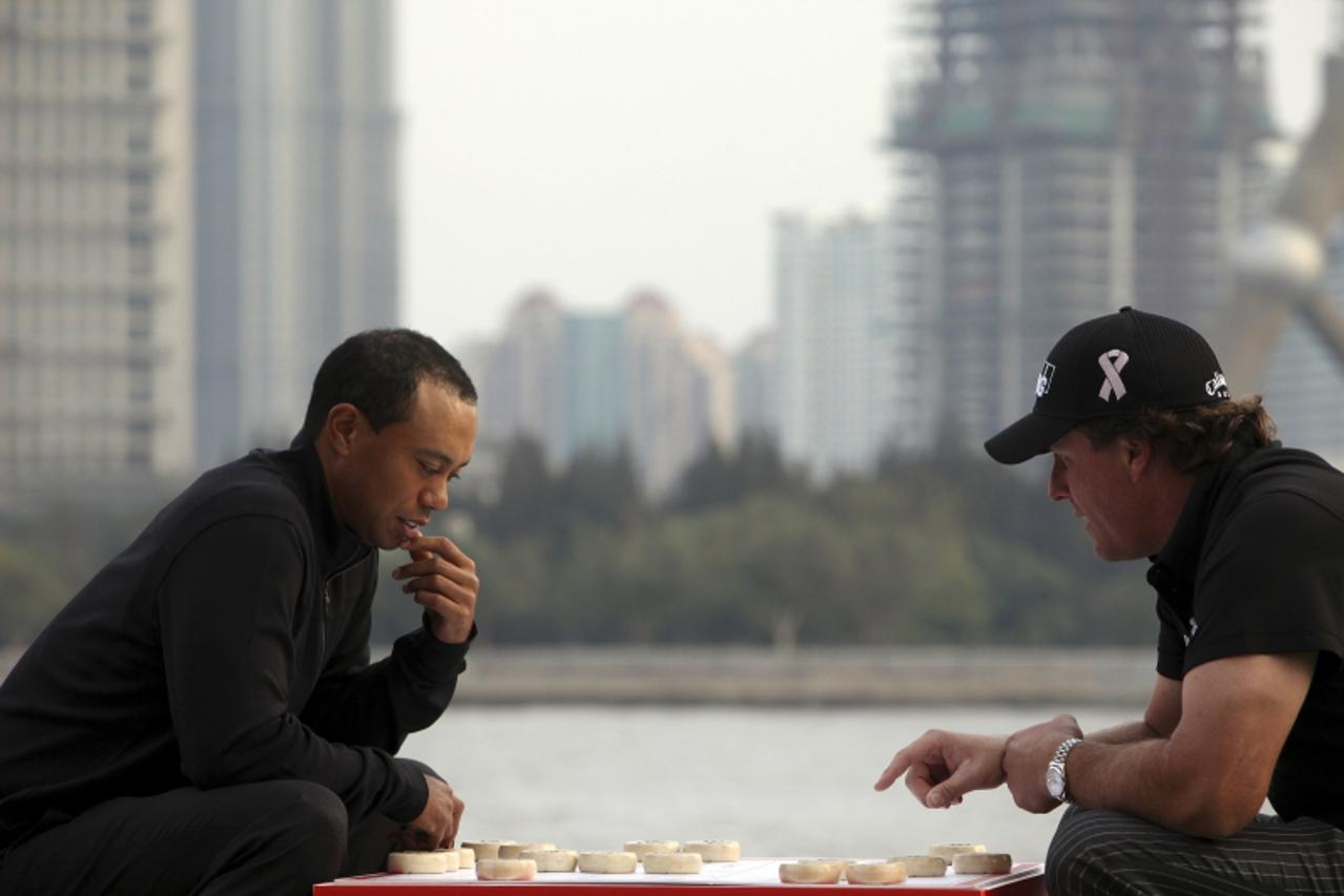 'Golfers Tiger Woods of the U.S. and compatriot Phil Mickelson pose for a photo near a Chinese chessboard during a promotional event for the upcoming HSBC golf tournament on the riverbank in Shanghai 