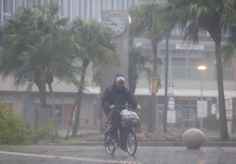 A man on a bicycle rides past in the heavy rain and wind caused by Typhoon Nanmadol in Miyazaki