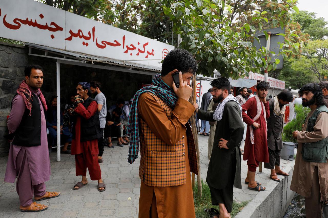 Family members of victims of last night's explosion wait in front of an emergency hospital in Kabul