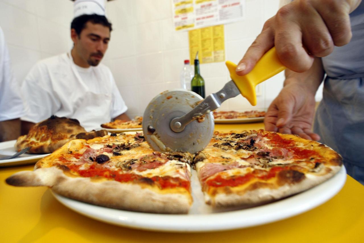 \'A student cuts a pizza in a pizza school during a course in Cap d\'Ail, southeastern France, October 5, 2006. World Food Day will be celebrated October 16, the day on which The Food and Agriculture 