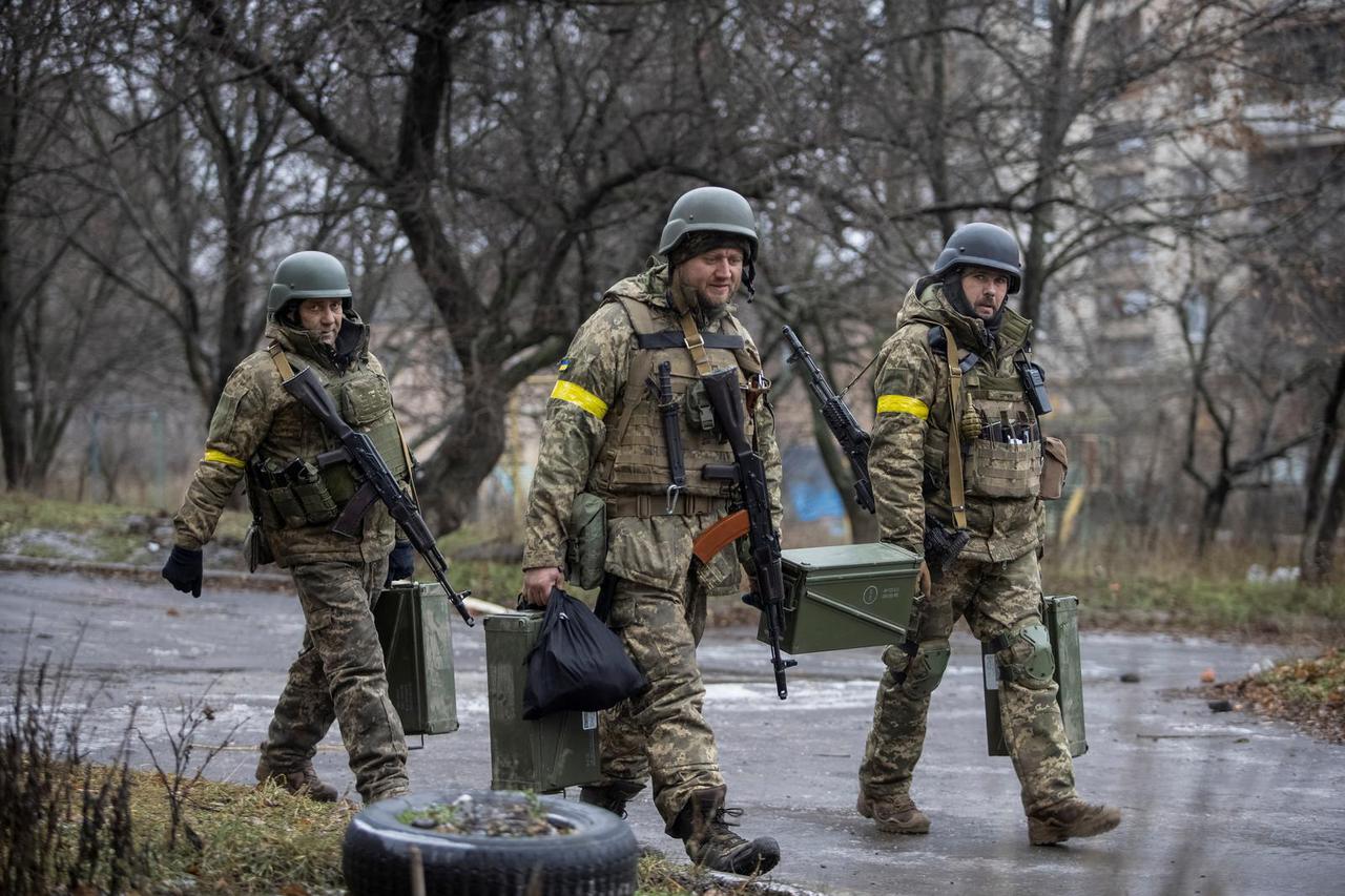 Ukrainian servicemen carry weapons in Bakhmut
