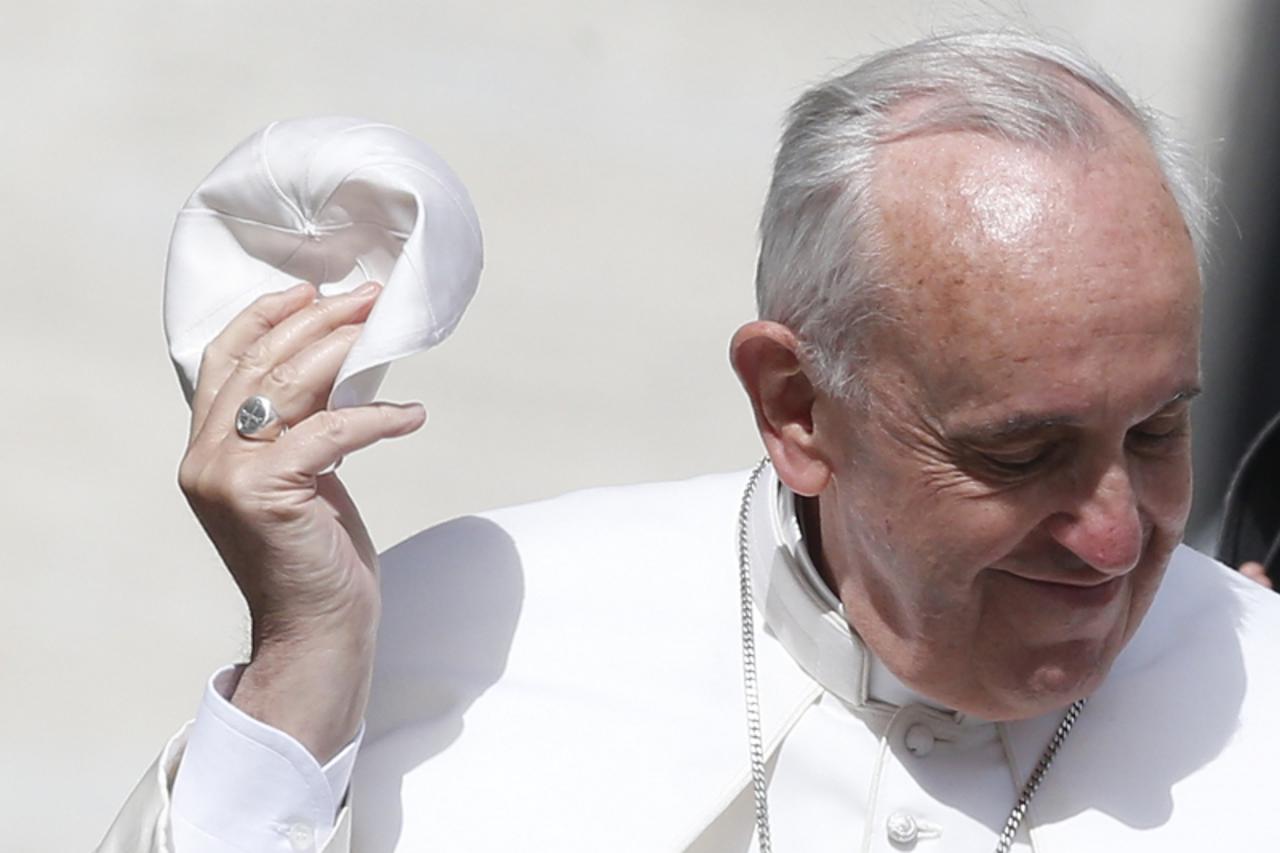 'Pope Francis holds his skull cap as he arrives to lead his Wednesday general audience in San Peter\'s square at the Vatican May 22, 2013. REUTERS/Tony Gentile (VATICAN - Tags: RELIGION TPX IMAGES OF 