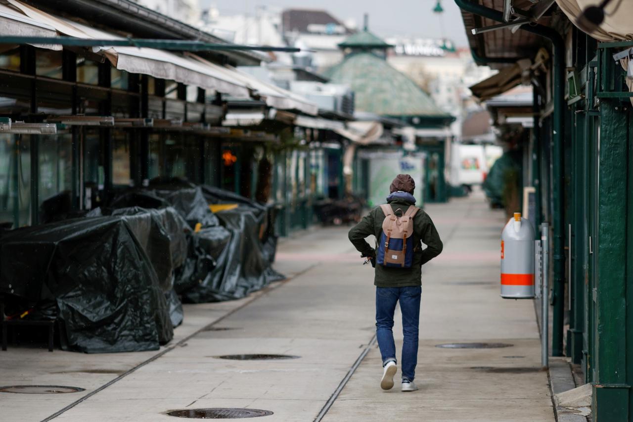FILE PHOTO: A person passes closed restaurants and shops at a market after the local government extended the lockdown due to the coronavirus disease (COVID-19) outbreak in Vienna,
