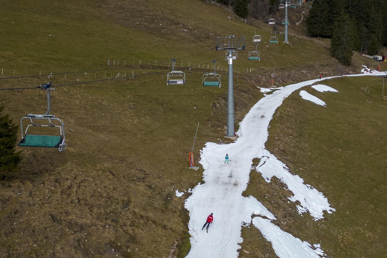 Skiers pass on a small layer of artificial snow in Leysin