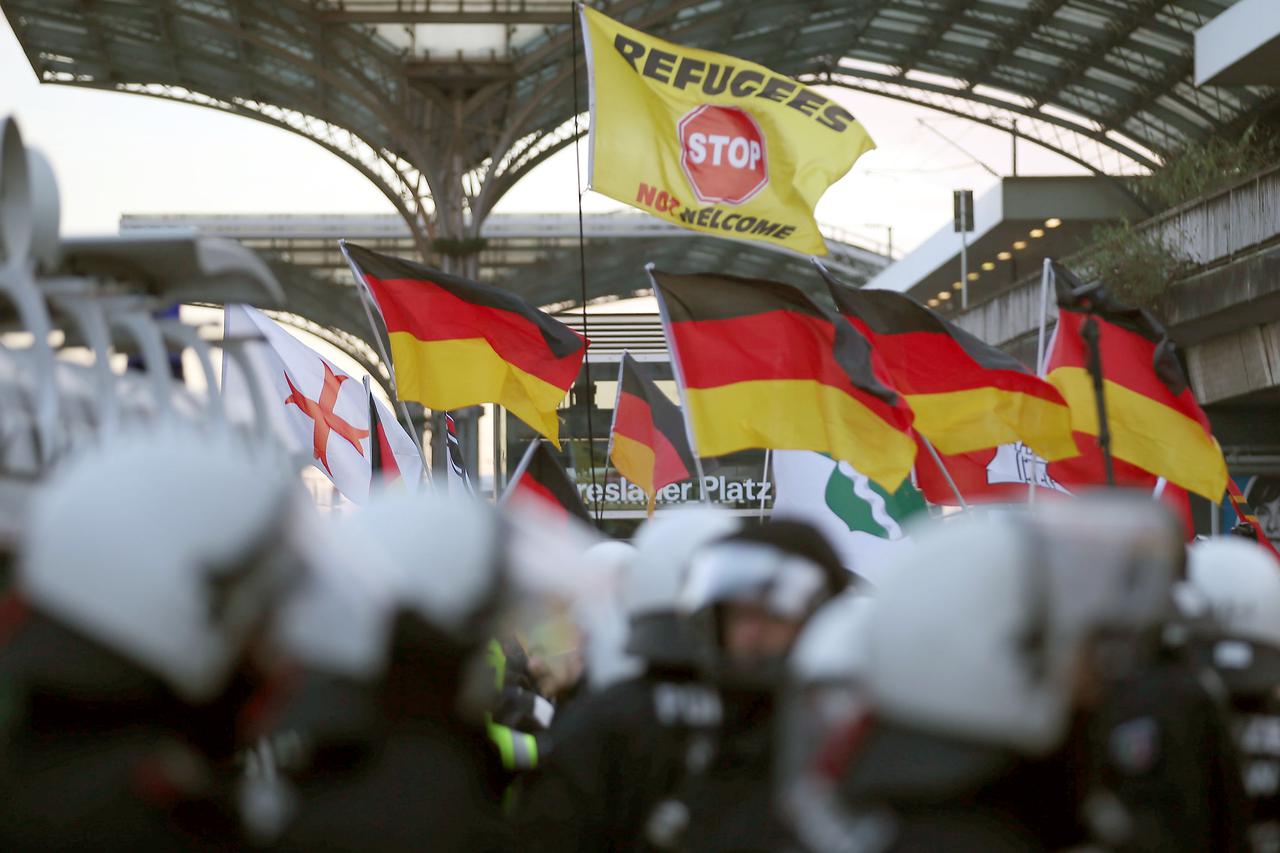 Police stand in front of right-wing demonstrators waving flags, at Breslauer Platz in Cologne, Germany, 09 Janaury 2016. In the wake of the sexual assaults around Cologne's main station on New Year's Eve, various groups held demonstrations on Saturday. PH