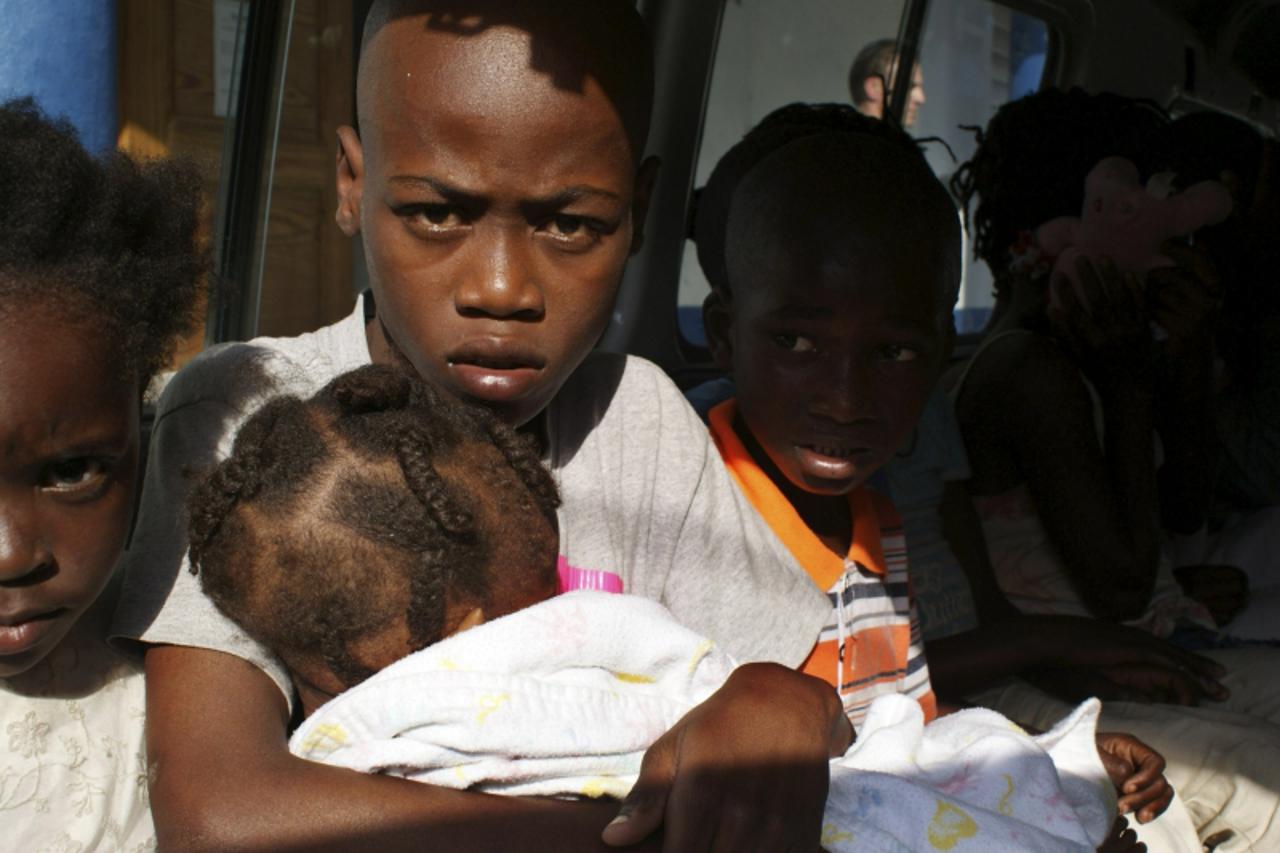 'Children suspected of being involved in an illicit adoption scheme sit in a local police car in Port-au-Prince January 30, 2010. Haitian police have arrested 10 U.S. citizens caught trying to take 33