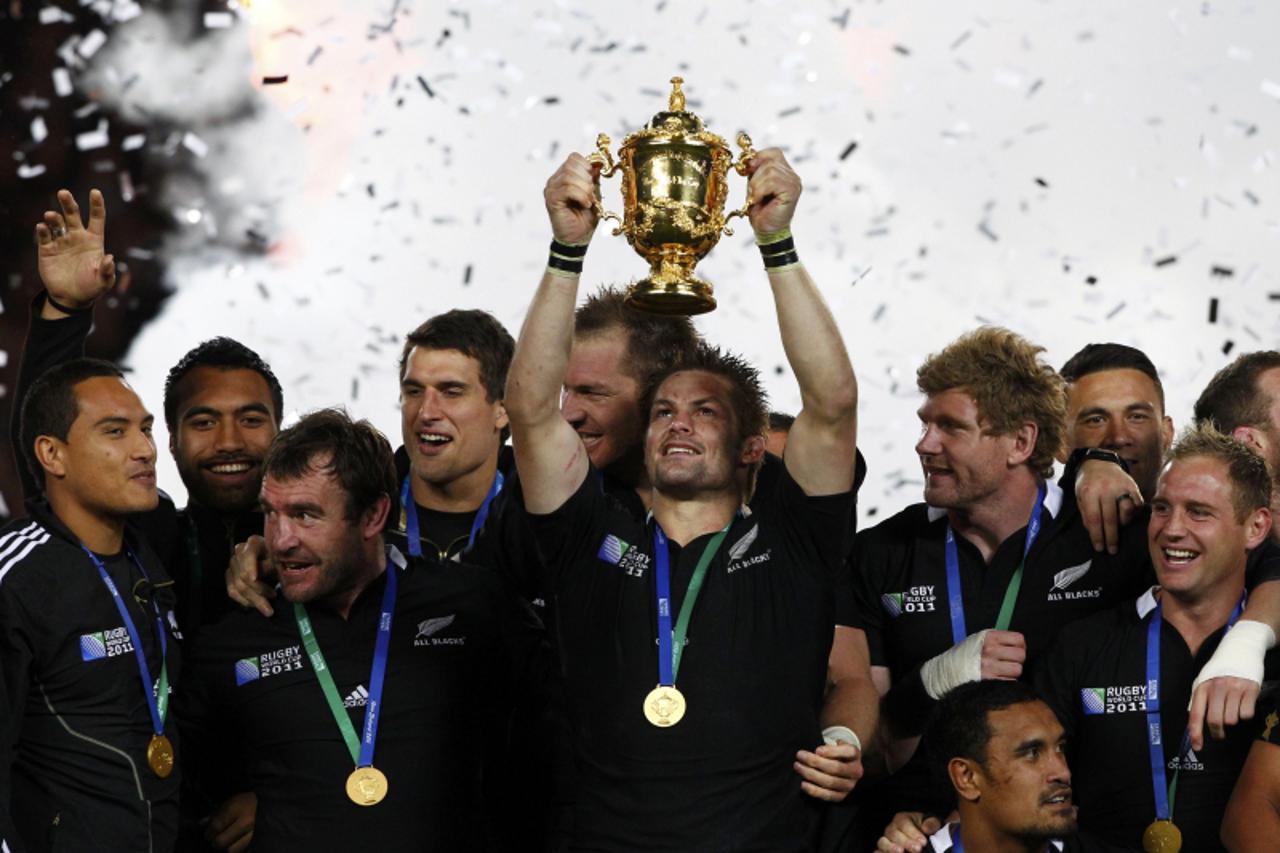 'New Zealand All Blacks captain Richie McCaw (C) holds up the Webb Ellis Cup after beating France to win the Rugby World Cup final match at Eden Park in Auckland October 23, 2011.   REUTERS/Mike Hutch