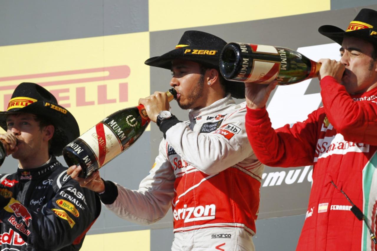 'McLaren Formula One driver Lewis Hamilton of Britain, Red Bull Formula One driver Sebastian Vettel (L) of Germany and Ferrari Formula One driver Fernando Alonso (R) of Spain drink champagne during th