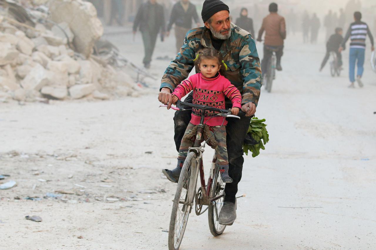 A man rides with his daughter on a bicycle in a rebel-held besieged area of Aleppo, Syria November 23, 2016. REUTERS/Abdalrhman Ismail