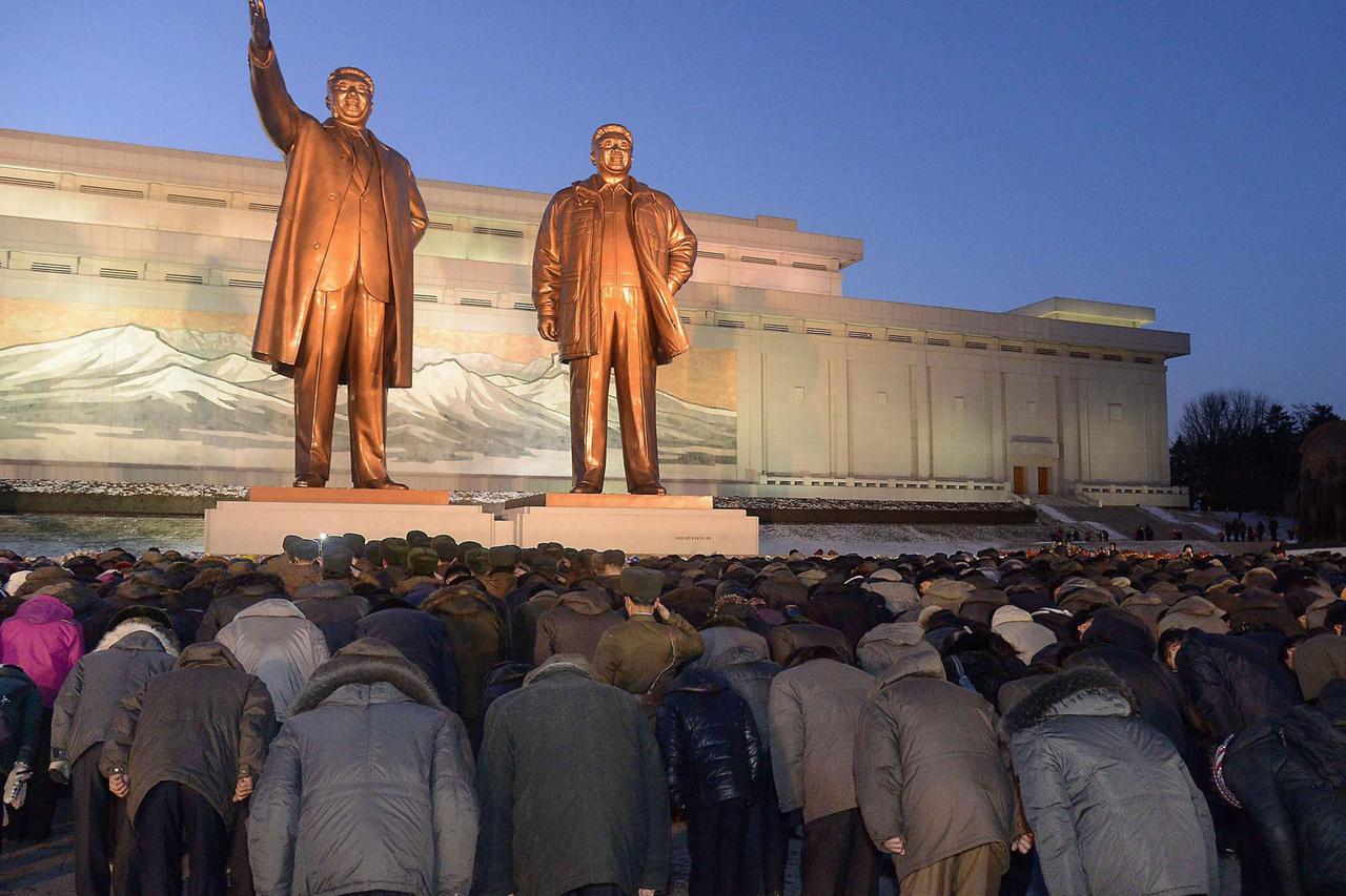 North Koreans bow to bronze statues of North Korea's late founder Kim Il Sung (L) and late leader Kim Jong Il at Mansudae in Pyongyang, in this picture taken on December 16, 2014 and provided by Kyodo December 17, 2014, to mark the third death anniversary
