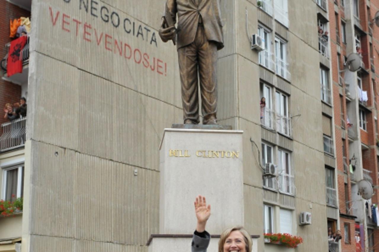 'US Secretary of State Hillary Clinton poses infront of a statue of her husband, former US president Bill Clinton, while driving from the airport to Pristina on October 13, 2010. Kosovo prepared a war